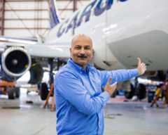 Nolinor-Photo-Employe A man in a blue shirt gestures towards an aircraft in a hangar, highlighting its features and maintenance work.