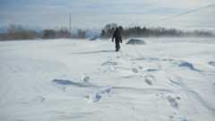 A person in a black snowsuit walking through blizzard conditions in southern Wisconsin in February 2011. (Credit: Groundhog Day Blizzard StoryMap; Courtesy of NOAA and the NWS.)