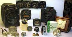 Pictured are a number of devices that contain radium luminous compounds. The devices include vintage military aircraft instruments, toggle switches, vintage consumer timepieces including a pocket watch and a travel alarm clock, instrument knobs, a circuit breaker, and drawer pulls.