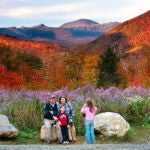 Wildflowers, fall foliage, and Mt. Washington serve as a backdrop for a family at Crawford Notch State Park in New Hampshire.
