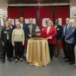 President Mun Choi, Provost Steven J. Berberich, Missouri Sen. Brian Williams, alumni and supporters Terry and Stan Freerks and members of the University of Missouri Board of Curators gather around Chancellor Kristin Sobolik as she rings a bell from the St. Louis Mercantile Library collection to mark the official reopening of University Libraries after the completion of a $12.1 million renovation project.