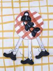 The image shows a red and white checkered plate with a group of black licorice candies arranged on it, set against a yellow and white grid-patterned background.