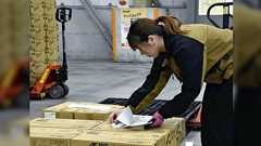 サイバー攻撃を受けたアスクルでは従業員が手元の資料を見ながら倉庫内に山積みにされた商品を探して台車に積み込み搬送している