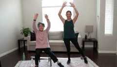 two women exercising in their living room with their arms raised two women exercising in their living room with their arms raised