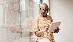 A woman using a tablet inside by a window A woman using a tablet inside by a window
