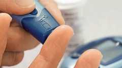 Eine Hand nutzt ein Blutzuckermessgerät, um einen Tropfen Blut vom Finger zu entnehmen, passend zum Thema Diabetes.