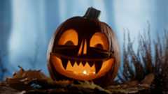 Pumpkin jack-o'-lantern carved for Halloween, lit from inside with candles.