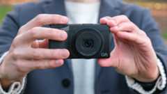 Ricoh GR IV compact camera held in a pair of hands