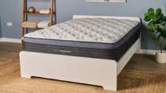 The Helix Midnight Luxe mattress placed on a white wooden bedframe, photographed in our blue coloured Testing Lab