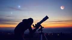 Image shows a man using one of the best telescopes for seeing planets set against a night sky