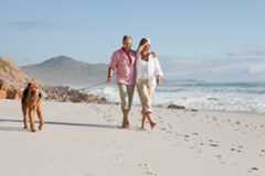 Couple walking dog by the sea