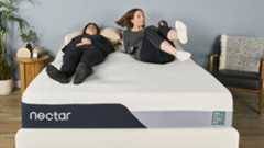 A person lies on the left side of the Nectar Premier Memory Foam mattress in our sleep studio, while another person jumps on the left hand side, testing motion isolation