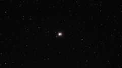 A bright dot of a star in the darkness of space with stars all around.