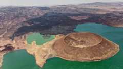 Aerial view of the Nabuyatom Volcano at the edge of Lake Turkana in northern Kenya showing its almost uneroded caldera, more than a kilometer wide. Black lava covers the land to the horizon.