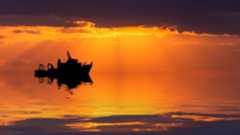 A research ship at sea at sunset.