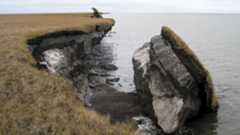 a photograph of a piece of Arctic permafrost collapsing into the ocean