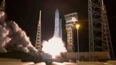 a white rocket lifts off from a launch pad at night.