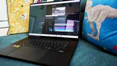 A black ASUS ProArt P16 laptop on a green sofa