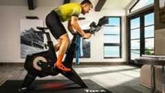 A man riding one of the best smart bikes indoors, the Garmin Tacx Neo Bike Plus