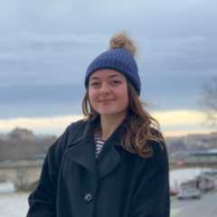 lauren wearing a wooly hat and coat in front of a wintery backdrop