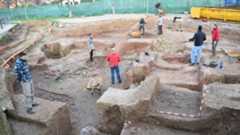 A group of people excavate on a dirt-covered area.