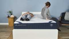 One Tom's Guide tester lies on her back on the DreamCloud Classic inside a blue-painted bedroom while another gets into bed, lies on her side and then lies on her other side