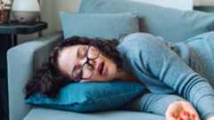 A woman naps on the sofa during the middle of the day
