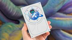A hand holding the Seagate Astro Bot Limited Edition Game Drive in ftong of a colorful background.