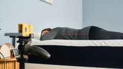 A laser pointer measures how well tester Ruth Jones's spine is aligned when stomach sleeping on the Nectar Premier Memory Foam Mattress.