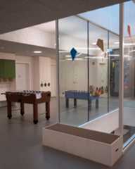 Dieser Alternativtext wurde KI-generiert: Ein Raum mit zwei Tischfußballspielen, die durch eine Glaswand getrennt sind. Die Wände sind hell und es gibt Dekorationen und Schilder an den Wänden.