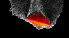 a space capsule shown lit up in orangish red is pushing downward through a tide of grayish swirls on a black background