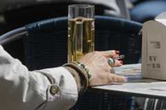 Una mujer en una terraza con un cigarro y una cerveza.