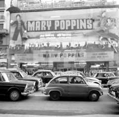 Una fila de coches pasa frente a un cine que anuncia el estreno de Mary Poppins en la década de 1960.