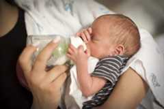 Momento en el que una madre alimenta a su bebé recién nacido con un biberón en casa.