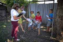 During a home visit with a family in eastern Ukraine, a social worker (far left) and a psychologist give the children colouring and exercise packets. During a home visit with a family in eastern Ukraine, a social worker (far left) and a psychologist give the children colouring and exercise packets.