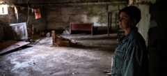 A woman stands in the basement shelter of the severely damaged school where she is deputy principal.