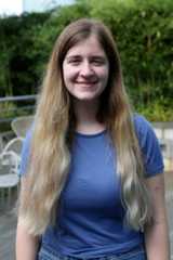a woman wearing a blue shirt standing outside smiling
