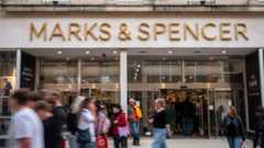 An M&S store front with shoppers walking past