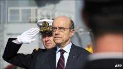 Alain Juppe reviews the troops onboard the Mistral high-tech amphibious helicopter carrier assault and command ship on 18 February 2011