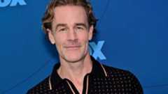 James Van Der Beek wears a black polo and stands in front of a blue background