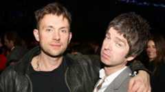Damon Albarn wearing a black leather jacket with his arm around Noel Gallagher at the Brit Awards 2013