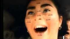 A woman is filming herself smiling as she drives at speed. There is a filter on her face, with the word "cute" dotted around her face