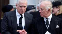 Andrew and King Charles talking as they walk. Charles points across Andrew and looks to the side while Andrew looks ahead. They both wear black suits, white shirts and black ties