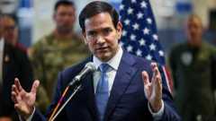 Marco Rubio, wearing a dark blue suit, stands behind two microphones, with both hands open