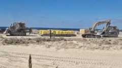 Two excavators are pictured on either side of a set of yellow blocks on sandy ground in Gaza