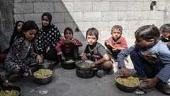 Palestinian children wait with pots to receive hot meals distributed by charity organizations
