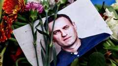 A portrait of Navalny sits among floral tributes and a candle in Berlin