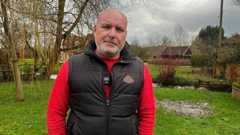 James is wearing a red long sleeve top and black vest