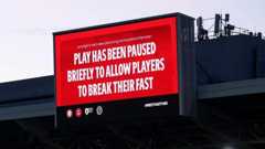 A board at a stadium announces 'Play has been paused briefly to allow players to break their fast'