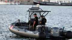 Two uniformed naval guards in a boat patrolling a port area